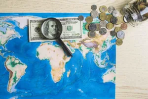 World map with currency and magnifying glass showing currency.