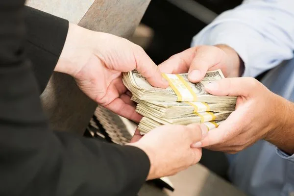 Transferencia de dinero de mano en mano con billetes agrupados