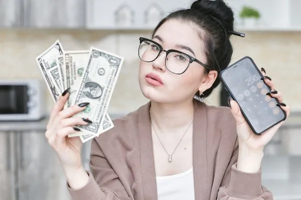 Mujer joven comparando efectivo y aplicaciones de transferencia de dinero