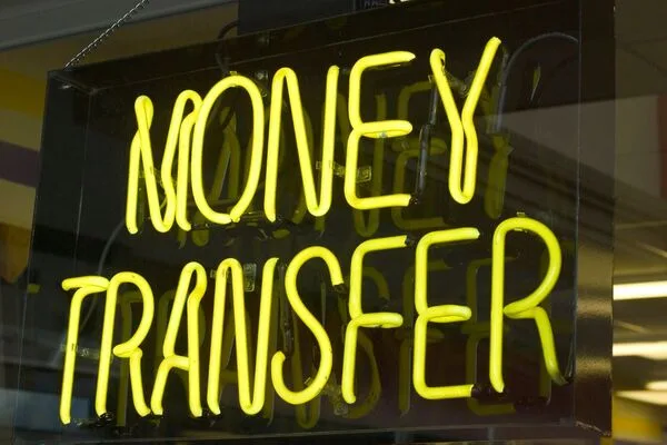 Bright yellow neon Money Transfer sign in shop window
