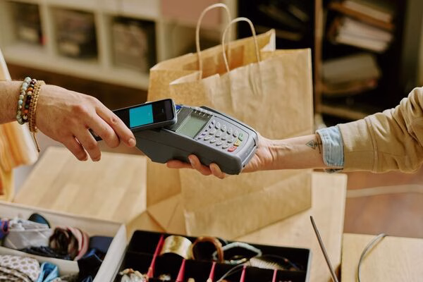Customer using smartphone for Cross Border Payments at retail checkout.
