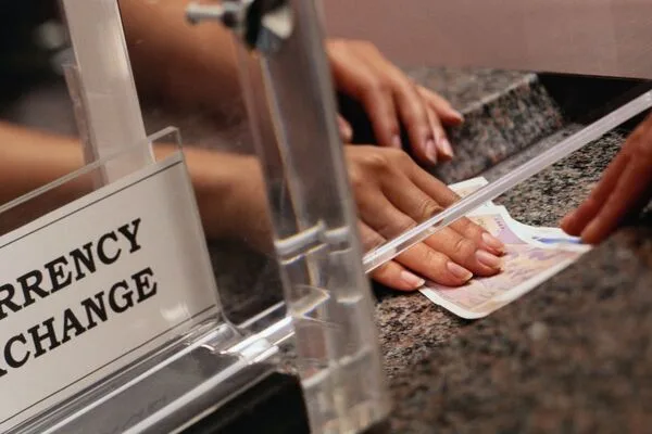 Manos intercambiando billetes en el mostrador durante el servicio de transferencia de dinero.
