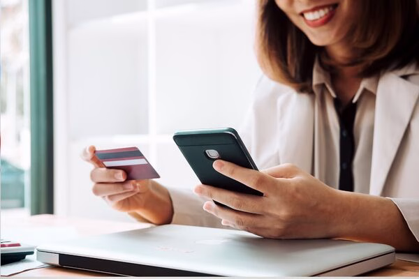 Woman using smartphone and card for Cross Border Payments.