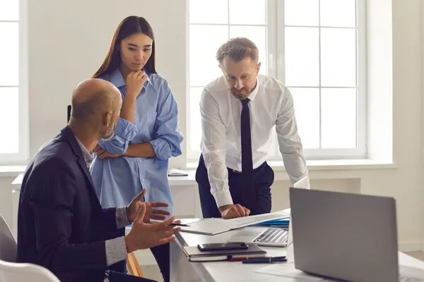 Colegas de negocios revisando informes de transferencias de dinero en una reunión de oficina.