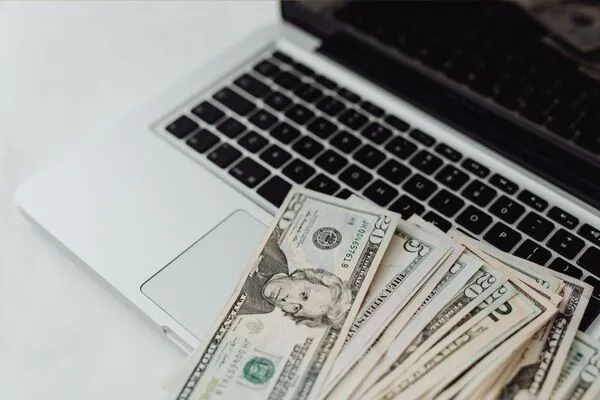 Dólares en efectivo colocados en una computadora portátil que simbolizan una transferencia de dinero en línea.
