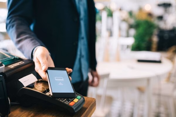 Cliente que utiliza un teléfono inteligente para pagos transfronterizos en la tienda.