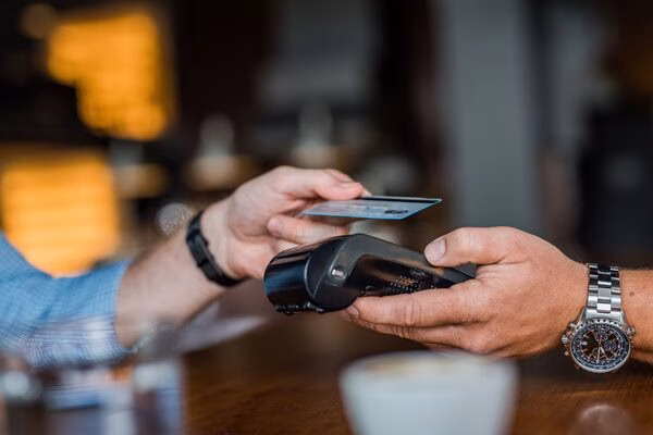 Man using card reader to process Cross Border Payments at café.
