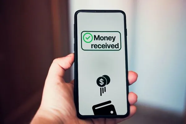 Pantalla móvil que muestra una transferencia de dinero exitosa con confirmación recibida.