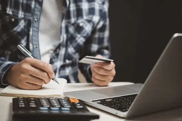 Money Transfer process shown with laptop, notebook, and calculator.