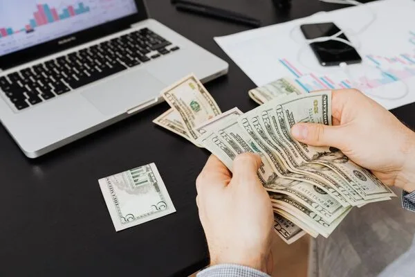 Persona contando billetes de dólares estadounidenses para una transacción de transferencia de dinero.
