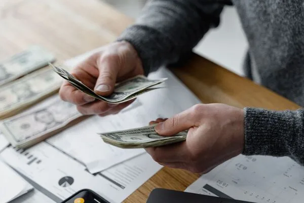Person counting cash during a Money Transfer process at desk.