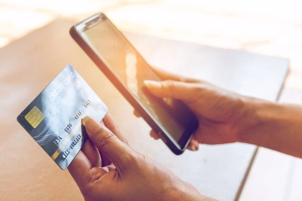 Person using smartphone and credit card for Cross Border Payments online.