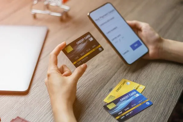 Persona que usa un teléfono inteligente y tarjetas de crédito para enviar dinero en línea.

