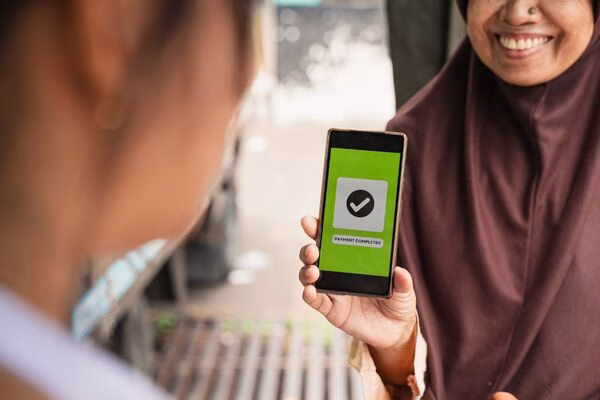 Woman confirming Cross Border Payments success on mobile phone screen.
