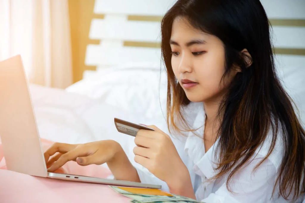 una mujer asiática verifica una transferencia internacional de dinero en línea con una computadora portátil