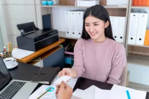 una mujer sonriente entrega un documento durante el proceso de cobro de un cheque
