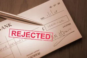 Bank check marked rejected highlighting common check cashing problems.