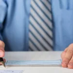 Businessman writing a personal check for upcoming Check Cashing service.