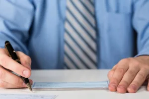 Businessman writing a personal check for upcoming Check Cashing service.