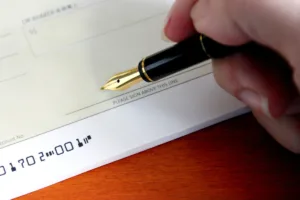 Hand holding pen before signing check for Check Cashing.