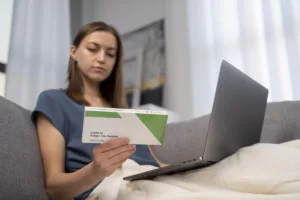 Woman sits on couch checking documents and Check Cashing details.