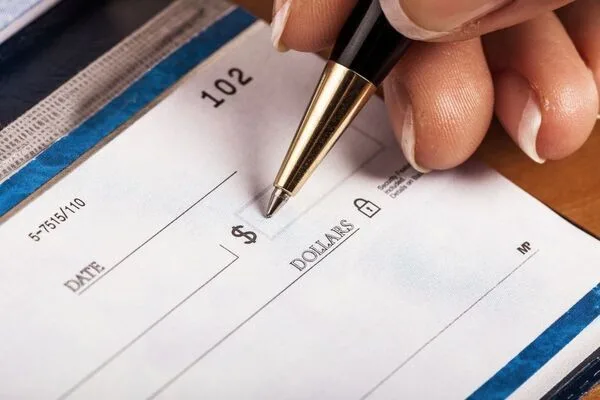 Hand holding pen filling blank check