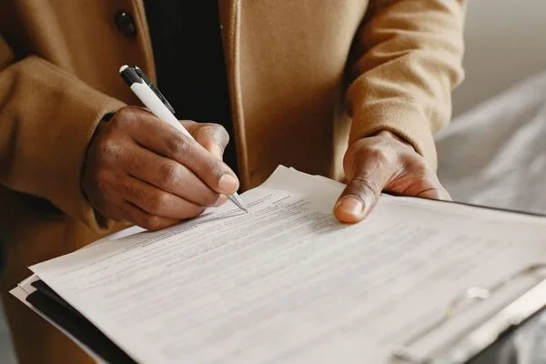 Hombre firma documentos importantes para la aprobación del servicio de cambio de cheques.