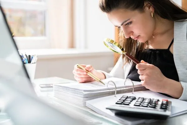Businesswoman carefully inspecting paperwork, auditing Check Cashing transactions.