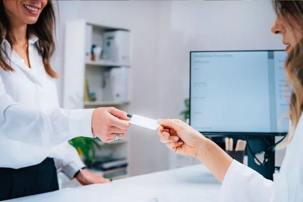 Cliente intercambiando tarjeta con cajero en oficina de cambio de cheques.