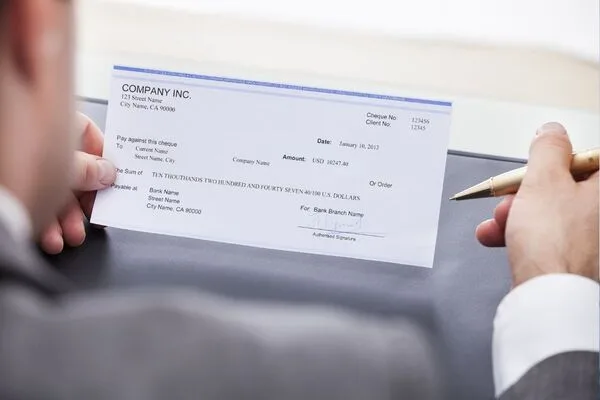 Man holding company paycheck preparing to Cash Checks safely.