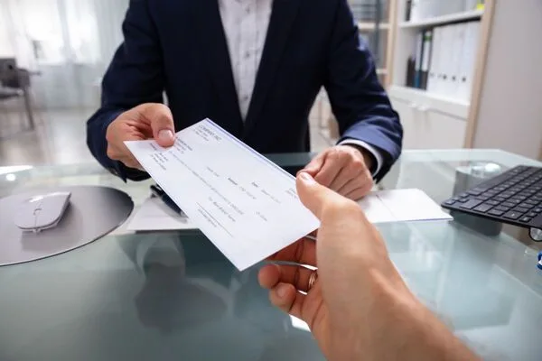 Man in suit accepts document from client to cash a check.
