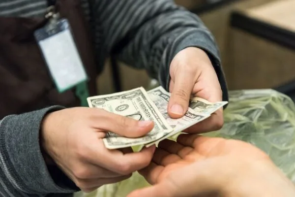Person receives dollar bills after deciding to cash a check.