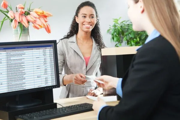 Mujer sonriente completando una transacción de transferencia de dinero en el mostrador del banco.