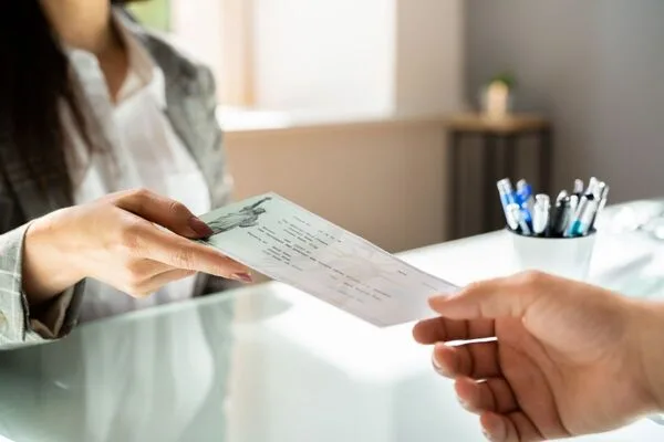 Woman handing over government check for quick check cashing service.