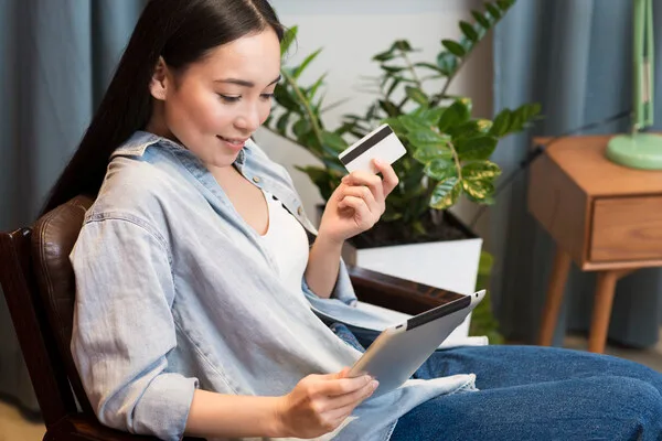 Woman holding card and tablet before cashing a check or money order
