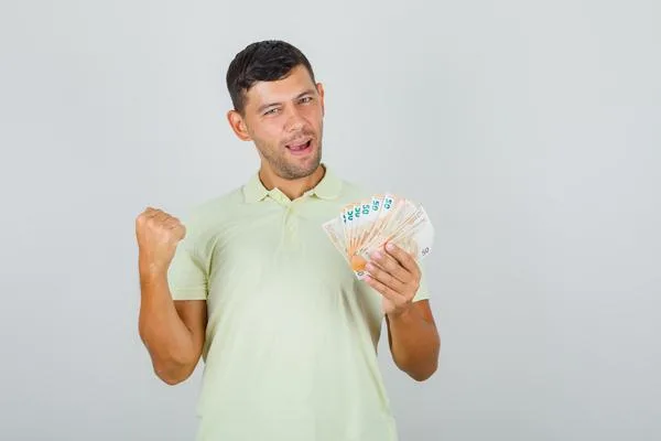 Hombre sosteniendo efectivo después de usar con éxito los servicios de cambio de cheques