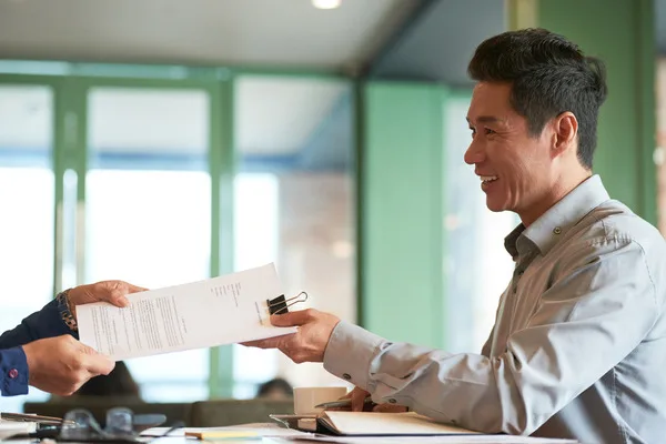 Business owner handing documents for check cashing
