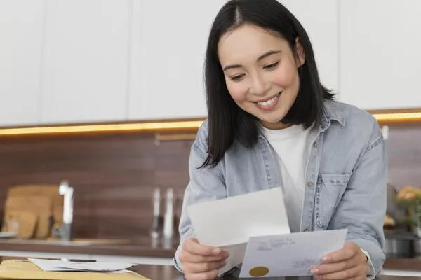 Una mujer lee un cheque de reembolso de impuestos en casa