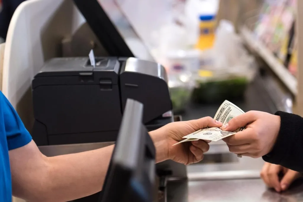 Manos intercambiando dinero en la tienda después de cobrar un cheque
