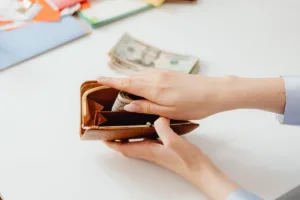 Persona que sostiene una billetera con dinero en efectivo para un giro postal