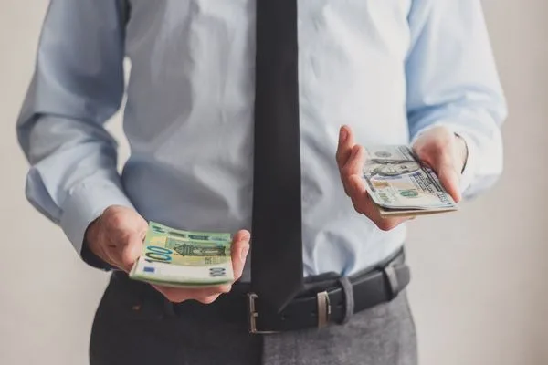 Businessman comparing money order with different currencies