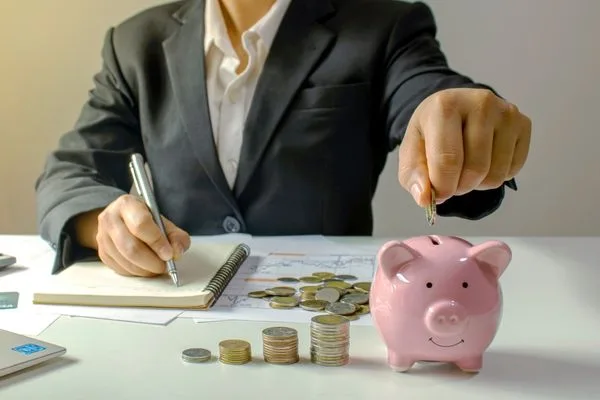 Hand placing money into piggy bank from check cashing