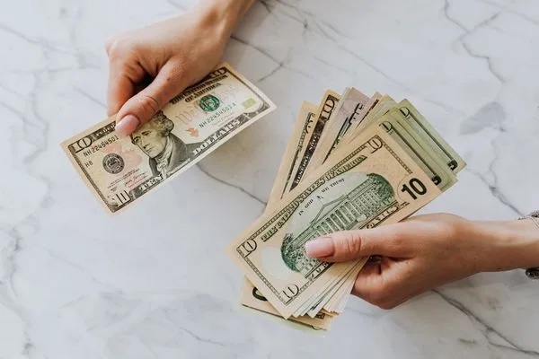 Manos preparando billetes de dólar para el pago de una orden de pago