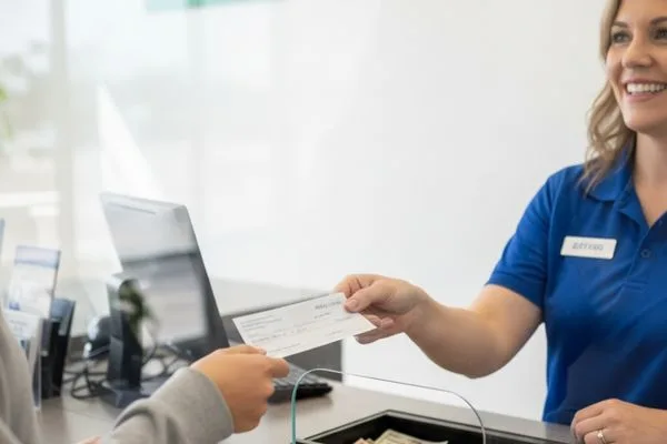 Un empleado ayuda a un estudiante a cobrar un cheque dentro de un centro de servicios financieros.

