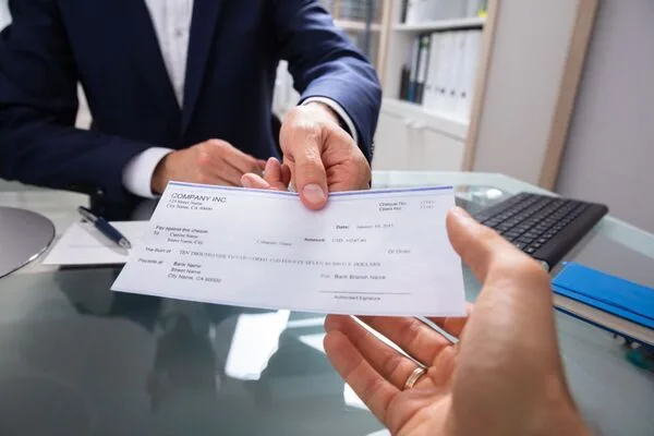 Empresario entregando cheque de pago para un servicio rápido de cobro de cheques.