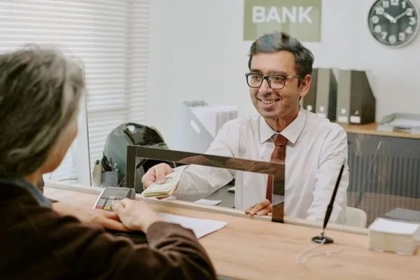 El cliente recibe el pago de una orden de pago de un empleado bancario amable.
