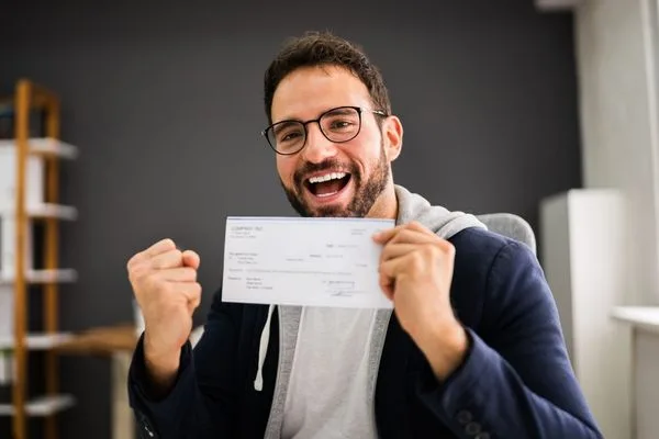 Happy man celebrating after successful Check Cashing with paycheck.