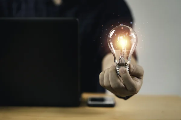Persona que sostiene una bombilla incandescente que simboliza una solución innovadora de giro postal.
