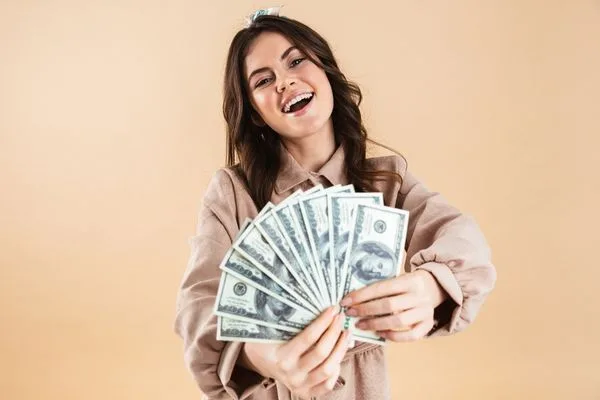 Smiling woman holding cash fan after successful Check Cashing.