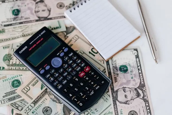Calculadora y billetes de dólar utilizados para cálculos de cobro de cheques
